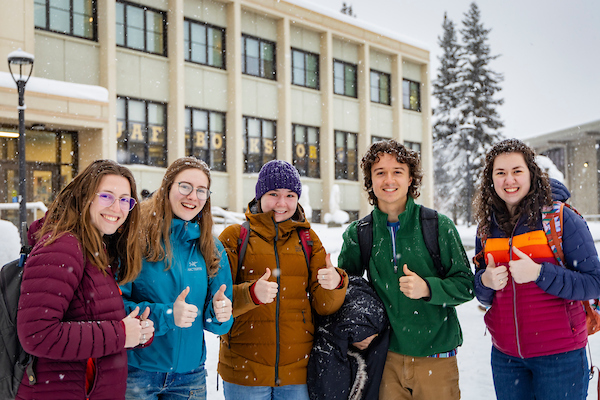A group of students pose for a photo on a wintery UAF campus